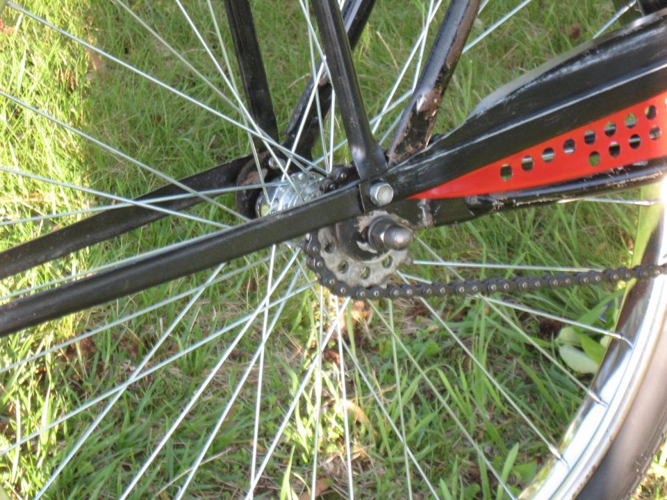 Bicycle rear wheel with silver spokes, black frame, and chain drive on grass