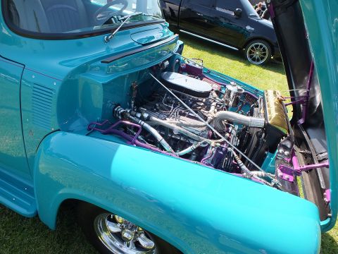 2003 Ford Crown Victoria - Detailed engine bay of a teal custom 1950s Ford pickup showing a V8 with purple accents, chrome headers and a gold reservoir.