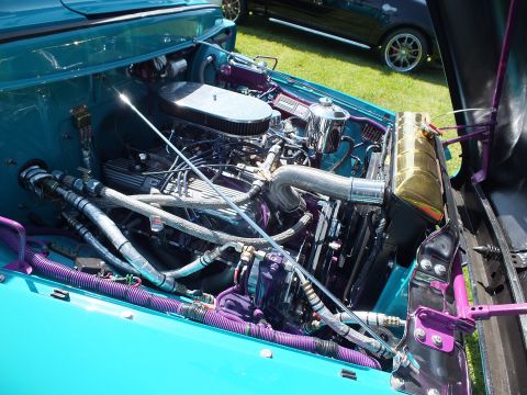 2003 Ford Crown Victoria - Close view of a teal custom Ford pickup engine bay with a chrome air cleaner, purple-coiled hoses and a gold reservoir tank.