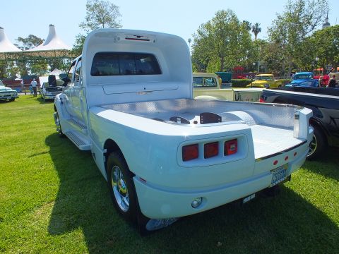2003 Ford Crown Victoria - rear of a white custom dually hauler shows a polished diamond-plate flatbed and a Ford tailgate badge on a show field.