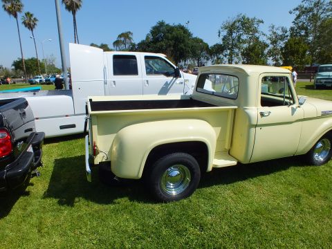 2003 Ford Crown Victoria - cream-colored vintage stepside pickup with chrome wheels rests on grass with other trucks and palm trees behind it.