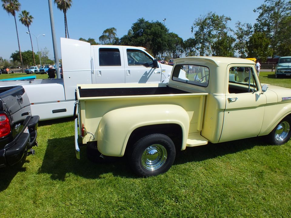 Cream vintage stepside pickup parked on grass at outdoor car show