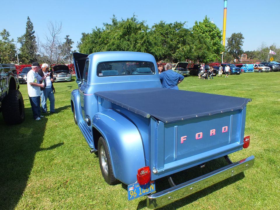 Blue classic Ford pickup with bed cover and FORD tailgate at car show