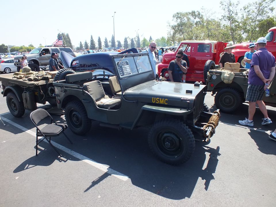 Olive-green USMC military jeep with cargo trailer at paved car show
