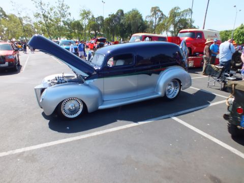 2003 Ford Crown Victoria - custom sedan-delivery hot rod painted dark blue over silver with wire wheels and an open hood, parked at an outdoor car show.