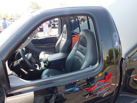 2003 Ford Crown Victoria - View through the open window of a black truck revealing gray leather sport bucket seats, one embroidered with a GT logo.