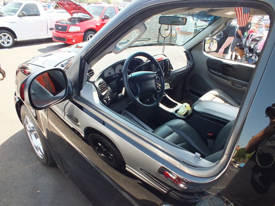 Interior of black truck seen through open window showing steering wheel and dashboard