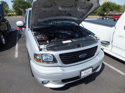 2003 Ford Crown Victoria - Front of a white Ford sport pickup with hood up exposing the engine, wearing California license plate 7J95893 at a car show.