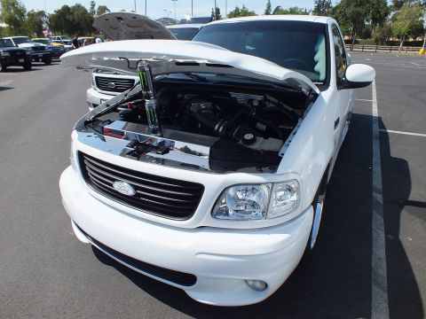 2003 Ford Crown Victoria - Front three-quarter view of a white Ford single-cab sport pickup with hood raised, exposing a supercharged-style engine.