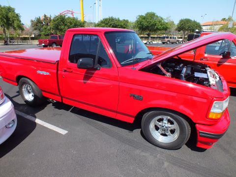 2003 Ford Crown Victoria - Front three-quarter view of a red Ford single-cab sport pickup with hood raised, exposing the engine bay at a car show.