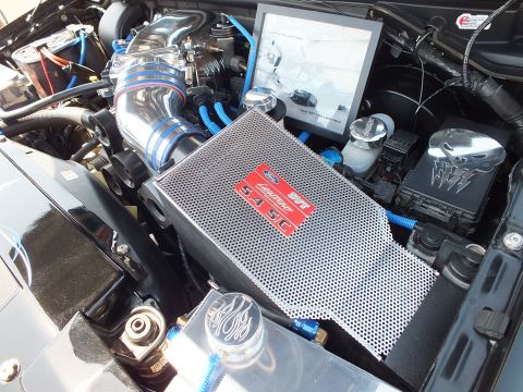 2003 Ford Crown Victoria - detailed engine-bay shot with a polished intake, blue fittings and a perforated metal cover bearing an SVT badge.