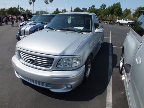 2003 Ford Crown Victoria - Front three-quarter view of a silver Ford pickup with a billet grille parked in a row at an outdoor car show.
