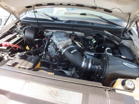 2003 Ford Crown Victoria - close look into a light-colored Ford truck's engine bay showing the intake manifold and black air intake tubing.