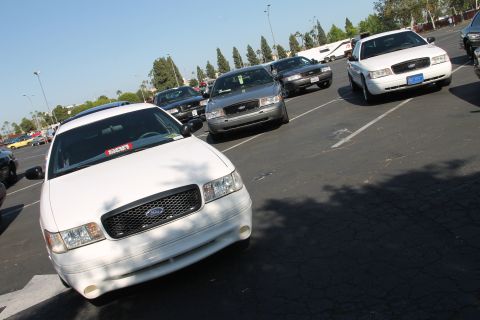 1992 Ford Crown Victoria - Multiple Ford Crown Victoria police cars are parked in a lot under a clear sky.