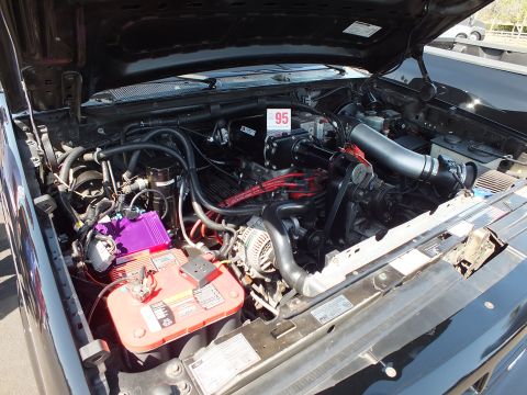 2003 Ford Crown Victoria - detailed engine bay view of a V8 with a red battery, purple coil, plug wires and alternator, marked with a 95 placard.