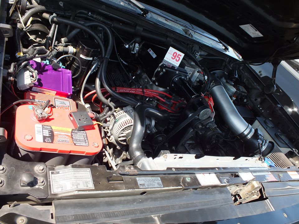 Engine bay close-up with red battery, purple coil pack and serpentine belt