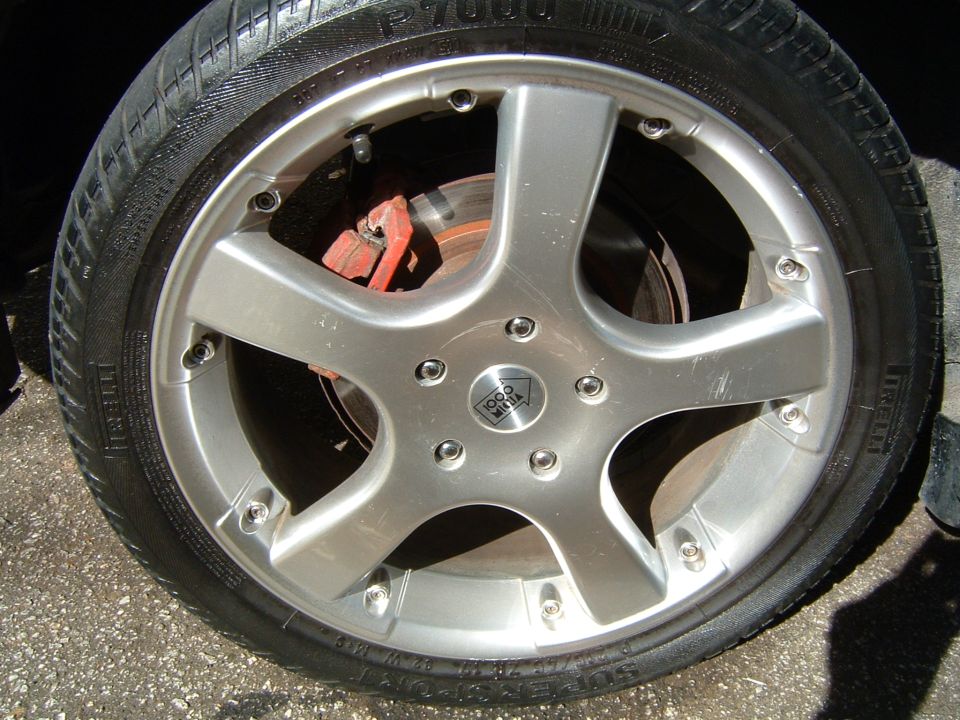 Silver 5-spoke aftermarket wheel with red brake caliper and Pirelli tire