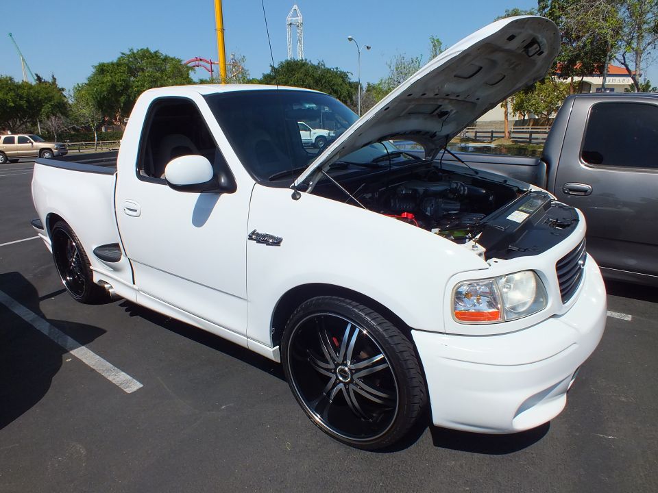 White Ford F-150 Lightning pickup with hood up on black-and-chrome wheels