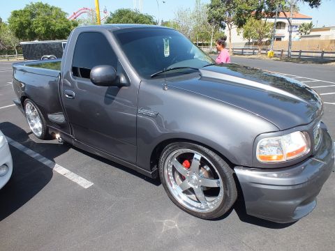 2003 Ford Crown Victoria - dark gray Ford F-150 Lightning regular-cab pickup, lowered with polished five-spoke wheels and red brake calipers, at a show.