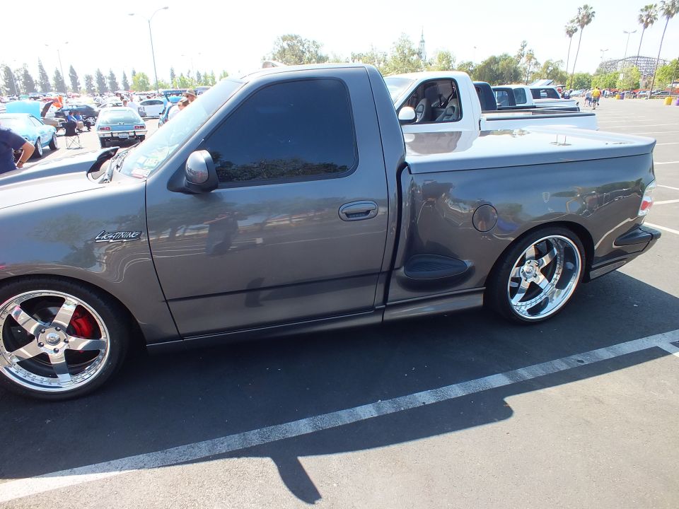 Side view of a charcoal Ford F-150 Lightning pickup lowered on chrome wheels