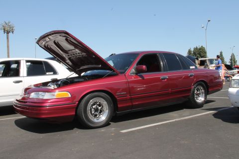 1992 Ford Crown Victoria - A red 1992 Ford Crown Victoria is parked with its hood open, revealing the engine bay.