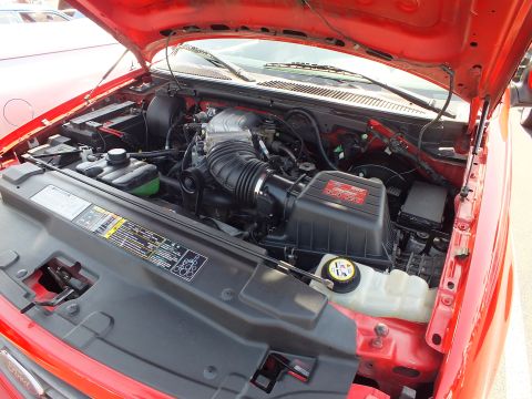 2003 Ford Crown Victoria - engine bay of a red Ford truck with the hood up, displaying a black supercharger intake assembly and reservoir.