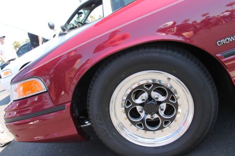 1992 Ford Crown Victoria - A red sedan with custom wheels is parked next to a white vehicle at an outdoor car show.