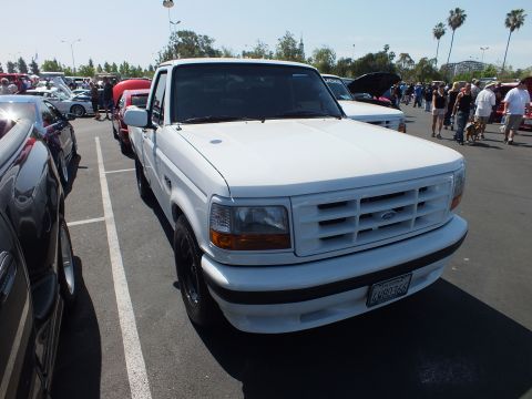 2003 Ford Crown Victoria - Front three-quarter view of a white Ford F-150 Lightning pickup parked at an outdoor car show.