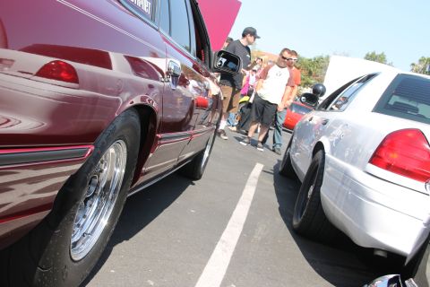 1992 Ford Crown Victoria - Two Ford Crown Victorias are parked side-by-side at an outdoor car show, with people milling around.