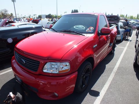 2003 Ford Crown Victoria - Front three-quarter view of a red Ford F-150 Lightning single-cab pickup at an outdoor car show.