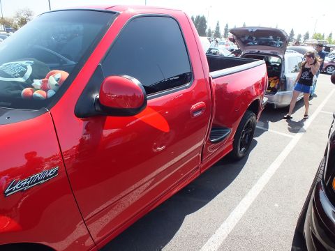 2003 Ford Crown Victoria - Side profile of a red Ford F-150 Lightning pickup showing its Lightning badge and black wheels.
