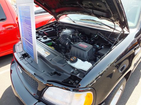 2003 Ford Crown Victoria - Engine bay of a black Ford Lightning showing the supercharged V8, with a blue info placard alongside.
