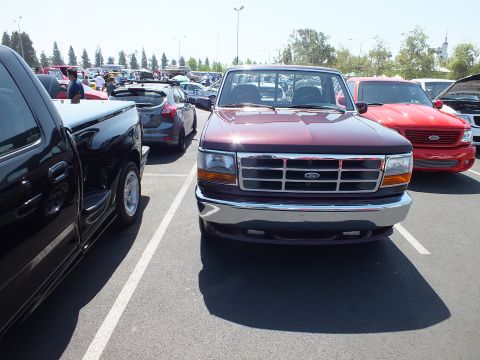 2003 Ford Crown Victoria - Head-on front view of a dark maroon 1990s Ford F-150 pickup parked at an outdoor car show.