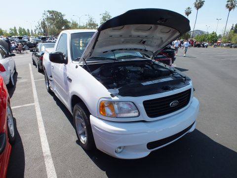2003 Ford Crown Victoria - Front three-quarter view of a white Ford F-150 Lightning pickup with its hood raised at a car show.