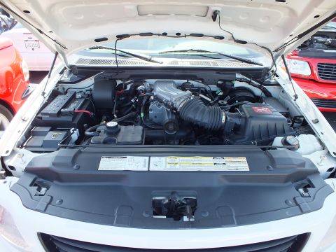 2003 Ford Crown Victoria - Engine bay of a white Ford Lightning pickup showing the supercharged V8 and emission labels.