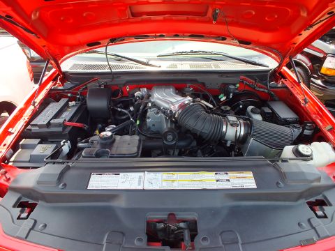 2003 Ford Crown Victoria - Engine bay of a red Ford Lightning pickup showing the supercharged V8 and underhood labels.