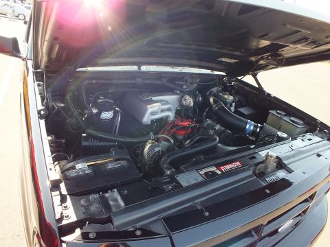 2003 Ford Crown Victoria - detailed truck engine bay shows a chrome cold-air intake, red valve covers and aftermarket performance components under the open hood.