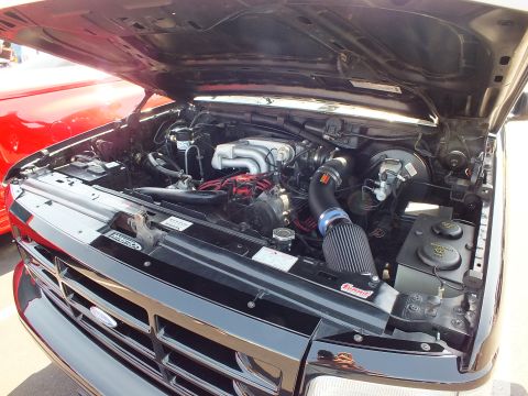 2003 Ford Crown Victoria - Ford pickup engine compartment with a black cold-air intake tube and red-painted intake sits exposed beneath the raised hood.