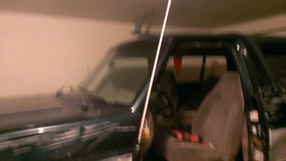 Interior view of a dark SUV, showing seats and dashboard area. A white pole is visible in the foreground