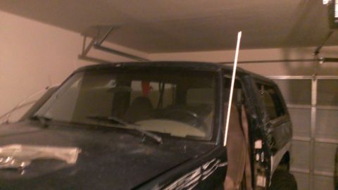 1994 Ford Bronco - The front-right quarter view of a dark-colored SUV is shown inside a garage.