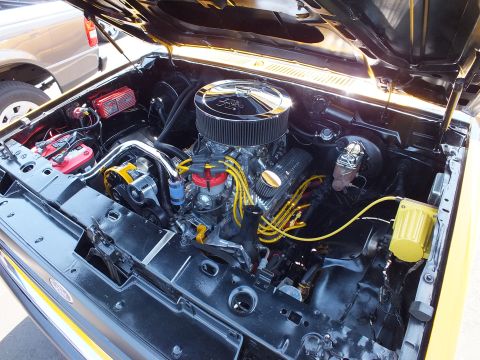 2003 Ford Crown Victoria - detailed V8 engine bay with a chrome air cleaner, yellow plug wires and a red coil sits under the open hood of a yellow truck.
