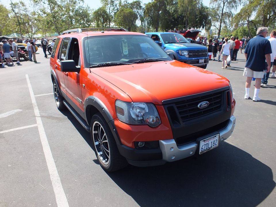 Red-orange Ford Explorer Sport Trac-style SUV with black grille at car show