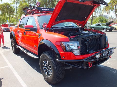 2003 Ford Crown Victoria - red and black Ford F-150 SVT Raptor crew cab sits at an outdoor show with its hood raised and a Yakima roof rack mounted above the cab.
