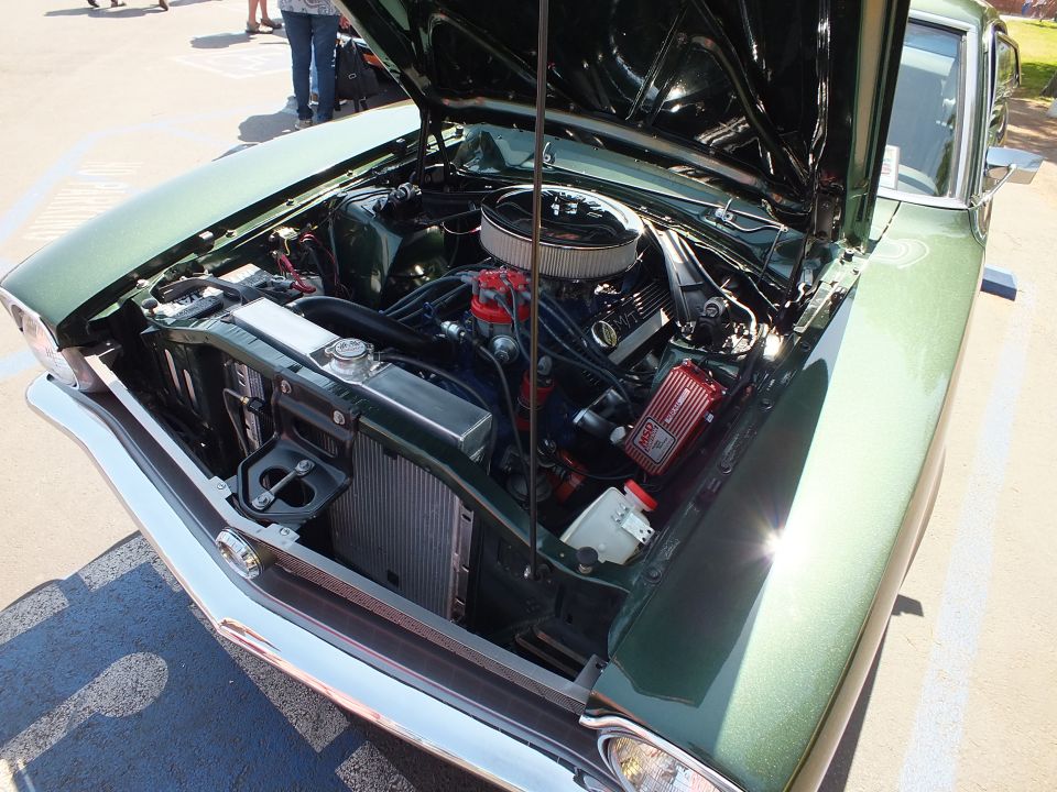 Engine bay of a green car with chrome air cleaner and chrome valve covers