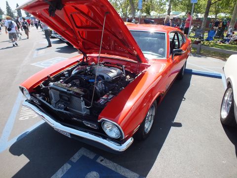 2003 Ford Crown Victoria - red Ford Maverick two-door coupe with its hood raised, showing the engine bay and a front license plate, parked at an outdoor show.
