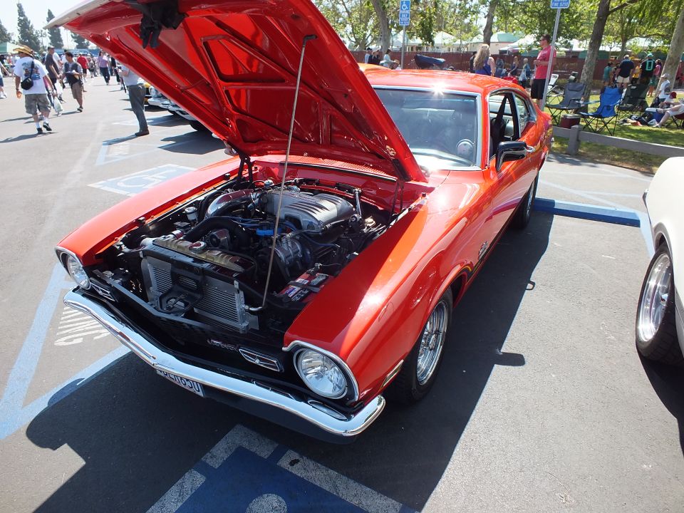 Red Ford Maverick coupe with open hood showing engine and front plate