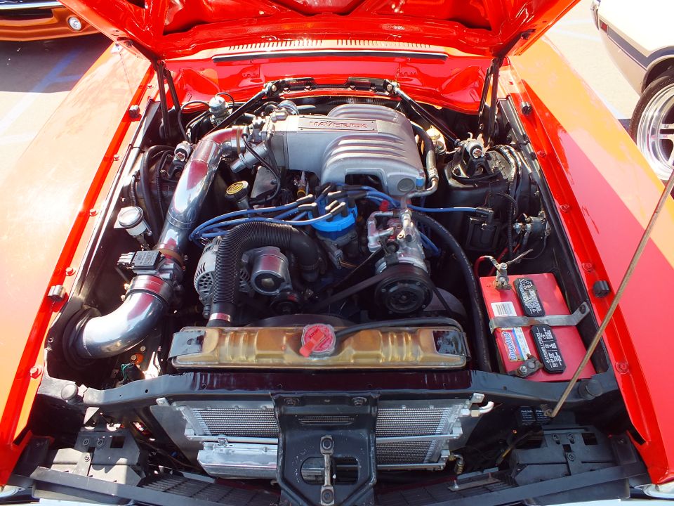 Engine bay of a red car with sequential fuel injection intake and blue plug wires