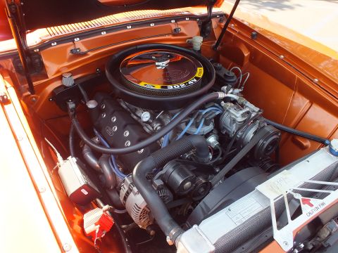 2003 Ford Crown Victoria - detailed V8 engine sits in an orange car's bay, topped by a round black air cleaner with blue plug wires and a chrome radiator shroud.