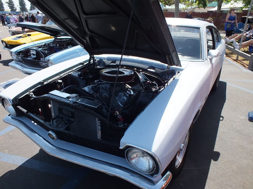 White compact car with open hood showing engine at car show