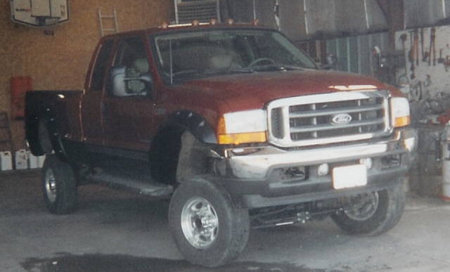 Red 2001 Ford F-350 pickup truck parked inside a garage